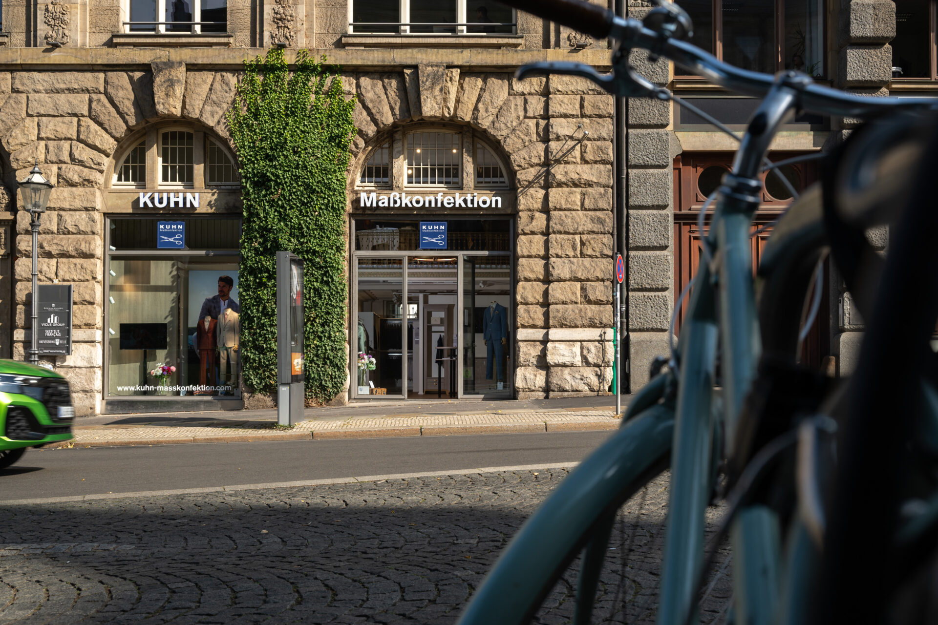 Außenansicht Kuhn Maßkonfektion Leipzig: Elegantes Schaufenster im historischen Denkmalschutz-Gebäude, unterstreicht die Exklusivität des Ladenbaus